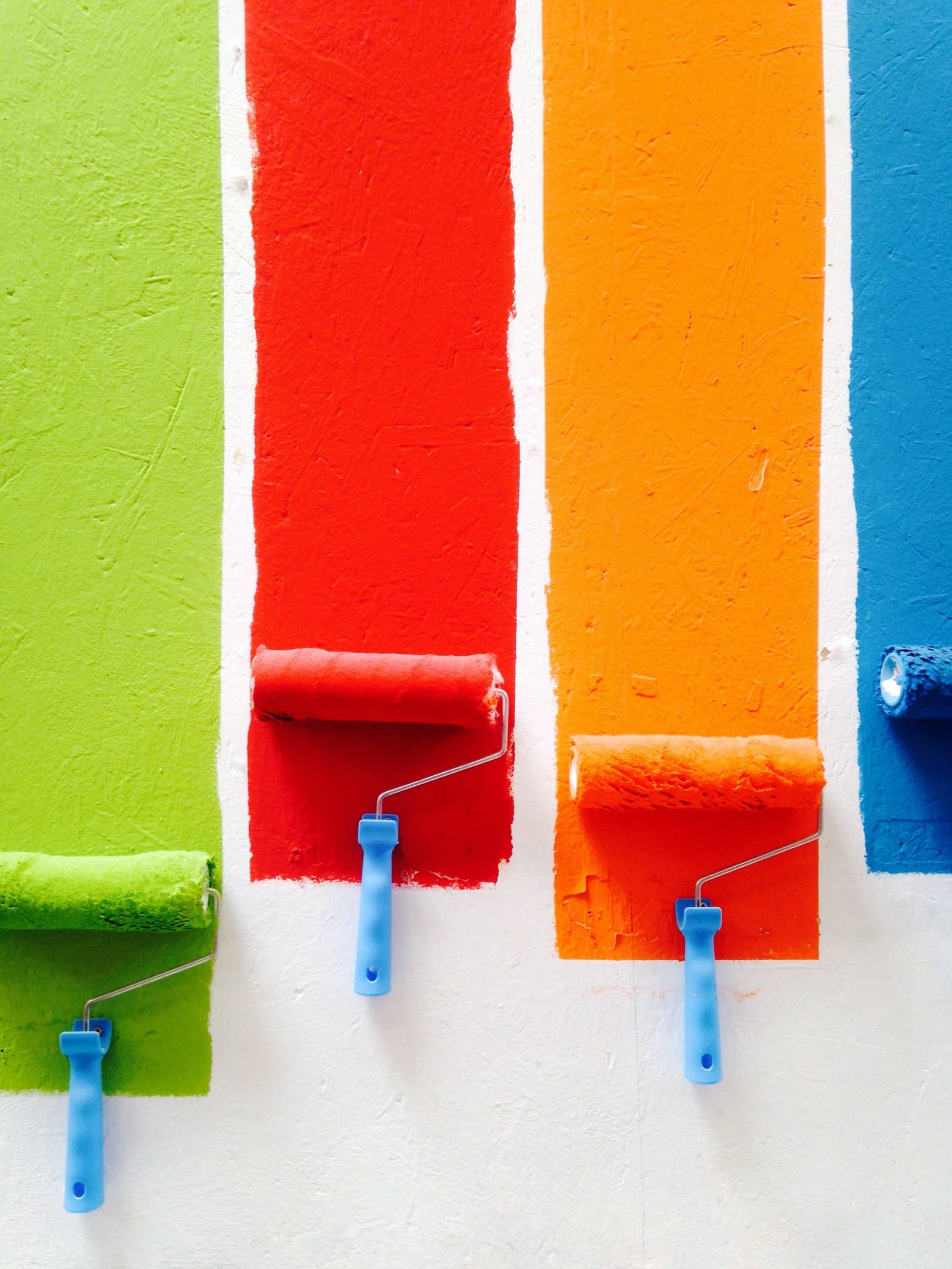 Paint rollers on white wall with multiple colours. House renovation.